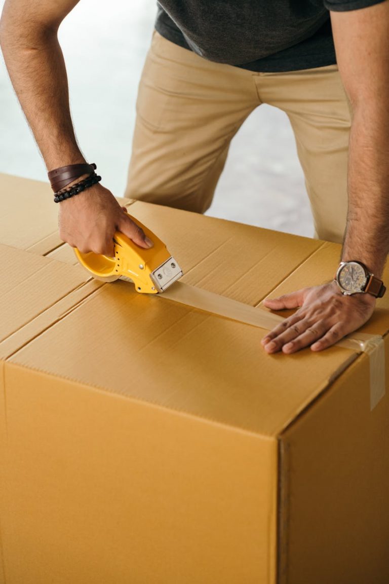 crop man sealing box with scotch tape